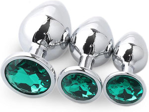 Three metallic silver butt plugs with faceted green gemstone base.